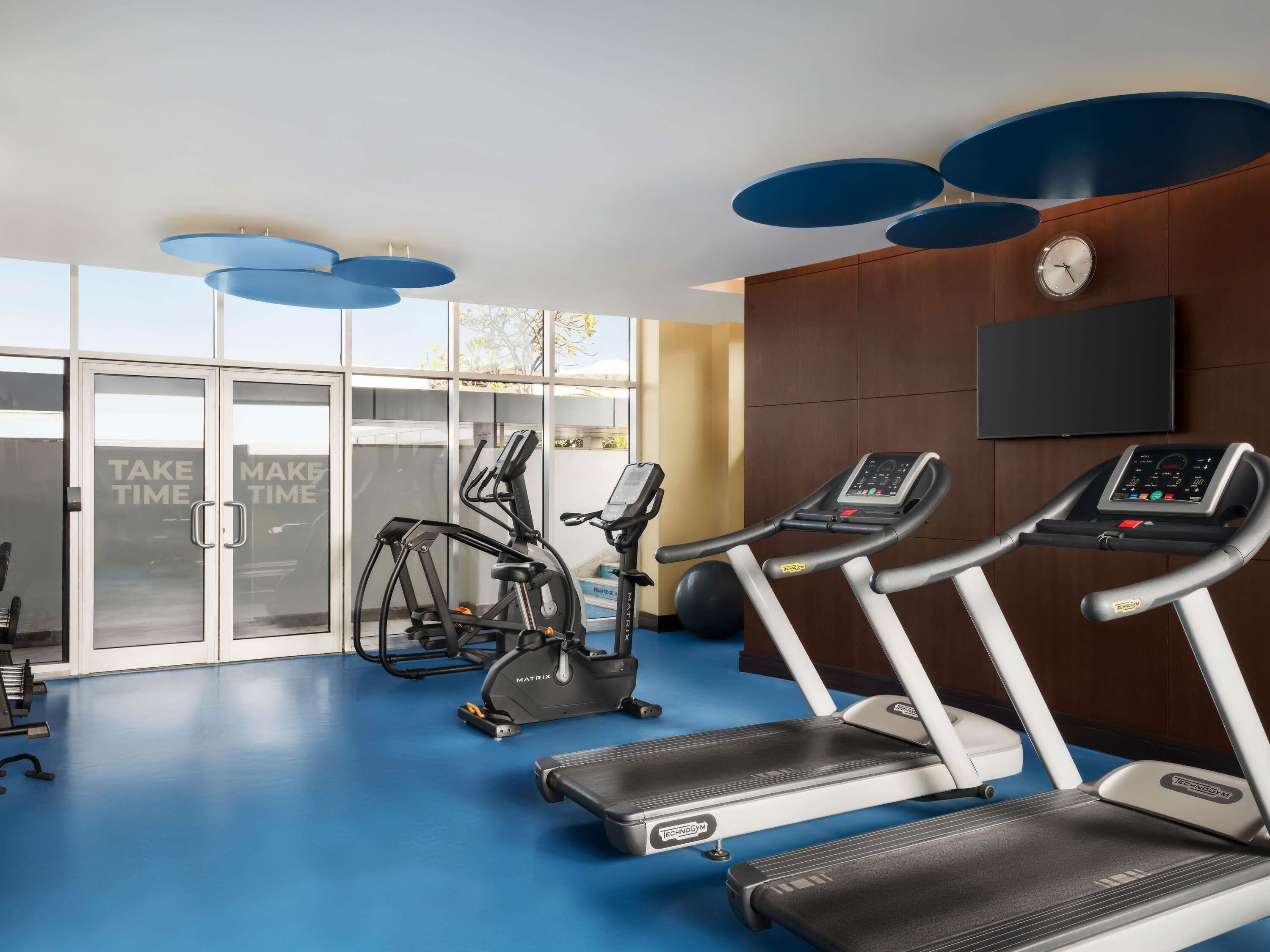 Een fitnessruimte met loopbanden, elliptische trainers en een televisie aan de muur.