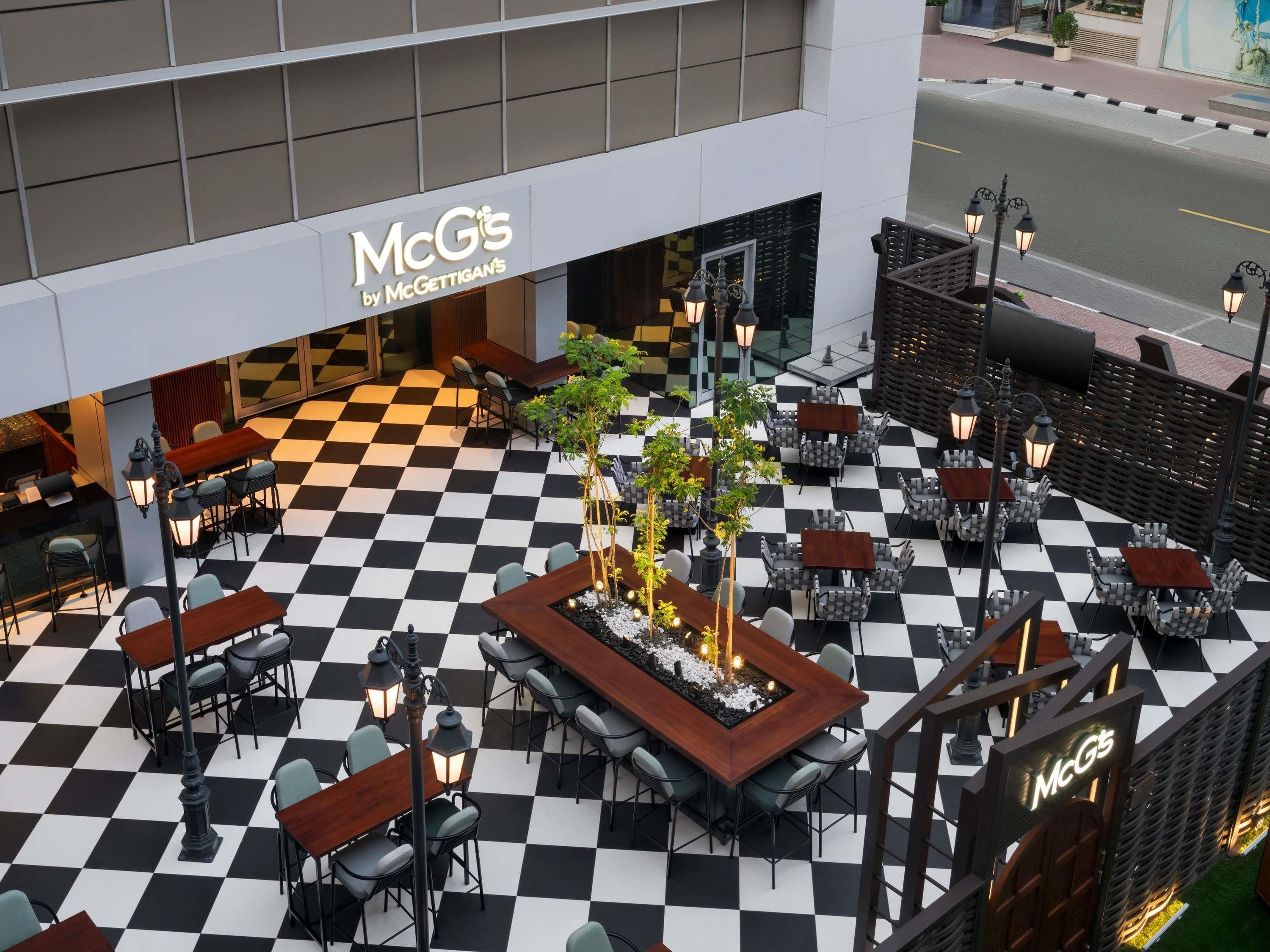A cafe with a checkered floor, outdoor seating, and a McG's sign.