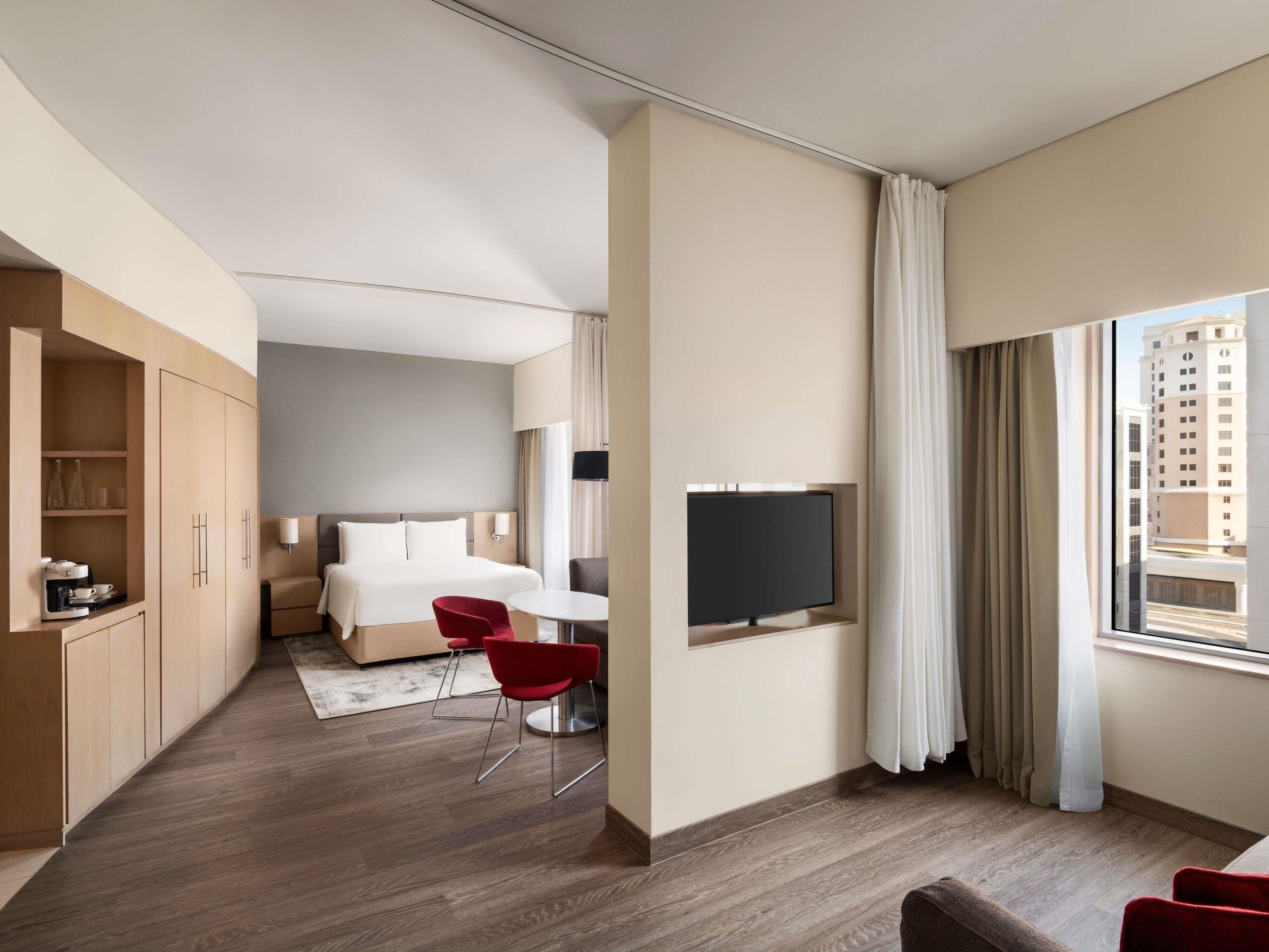 A hotel room with a bed, a TV, a desk, and a chair.