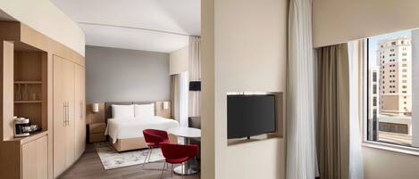 A hotel room with a bed, a TV, a desk, and a chair.