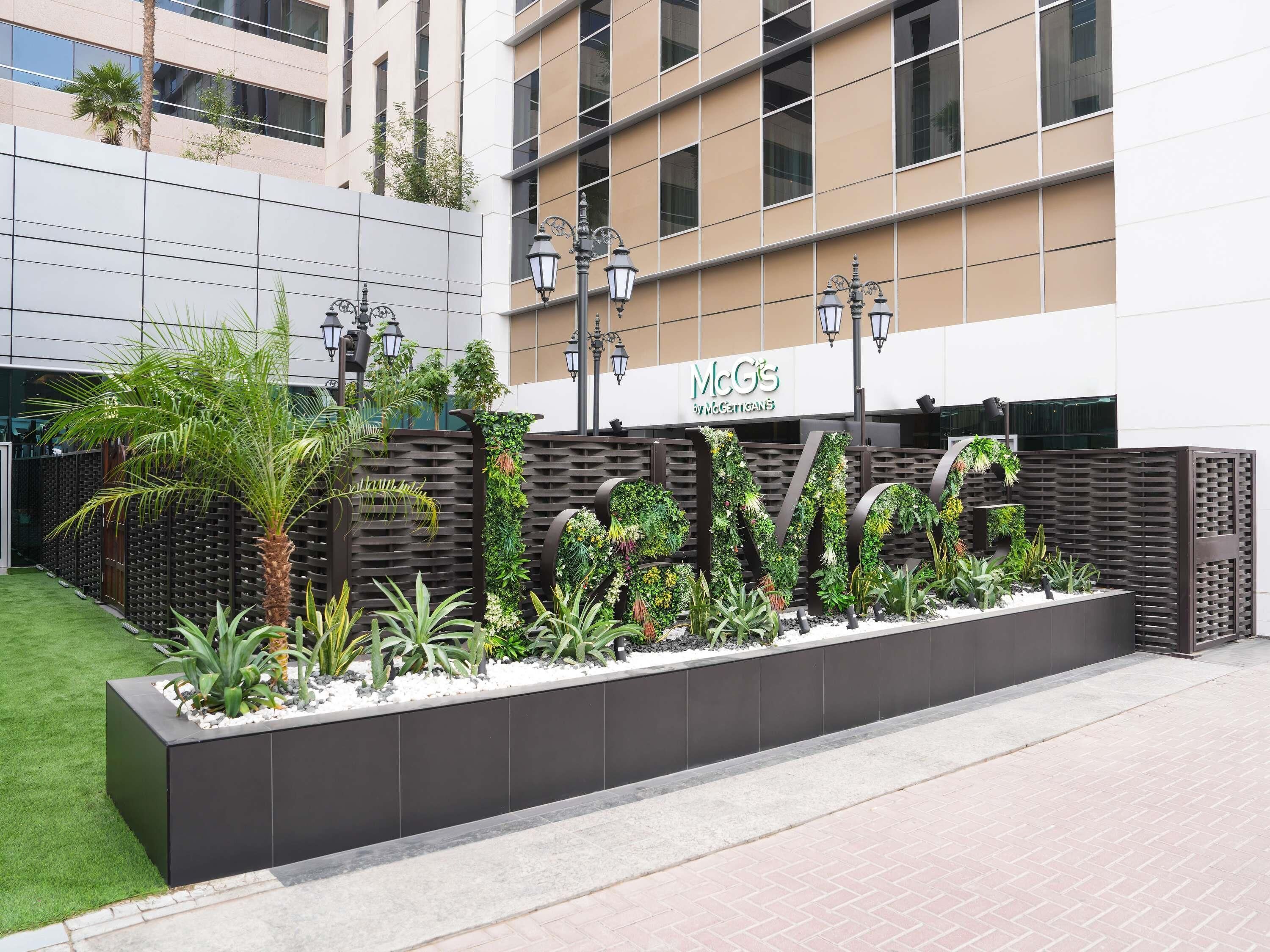 A modern building with a McGills sign, a landscaped garden with various plants, and a brick pathway.