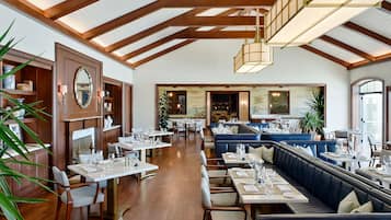 A spacious restaurant with high ceilings, wooden beams, and a mix of tables and booths.