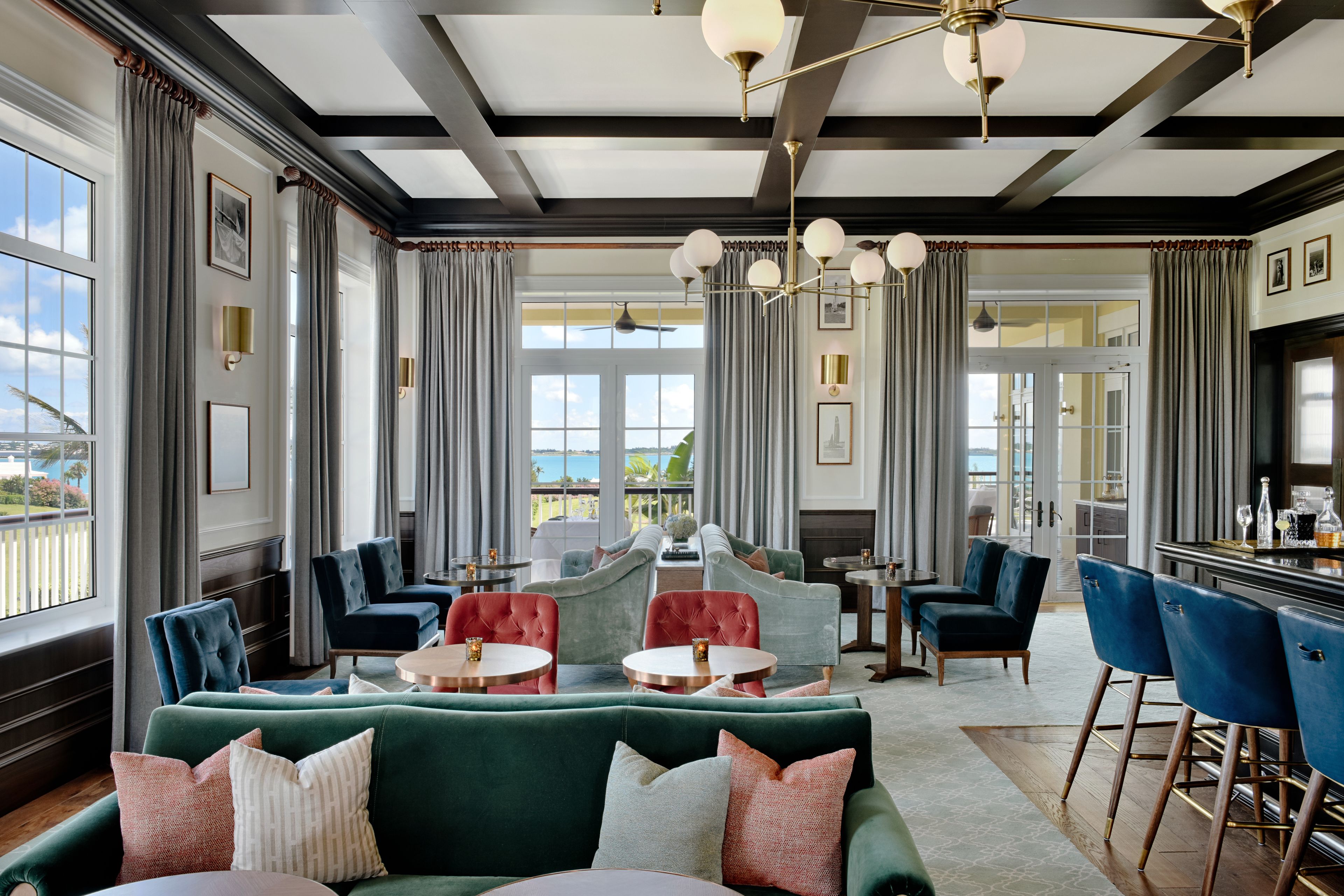 A spacious lounge area with a green sofa, red and blue chairs, and a bar area.