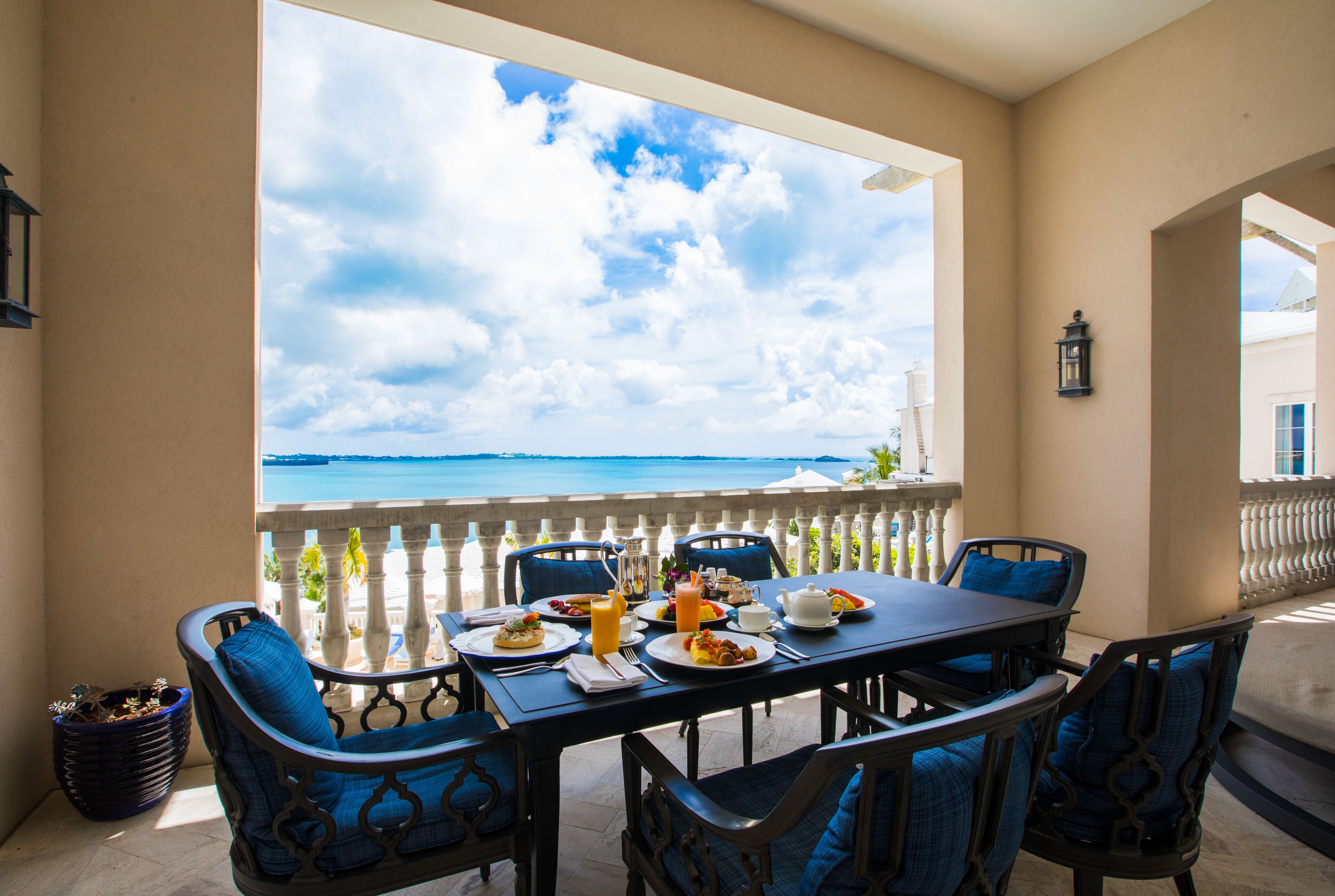 A dining area with a table set for breakfast, overlooking a scenic view of the sea.