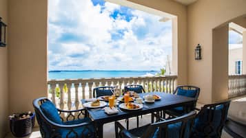A dining area with a table set for breakfast, overlooking a scenic view of the sea.