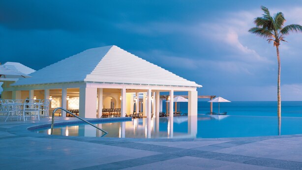 Un resort con piscina, sillones de descanso y una palmera.