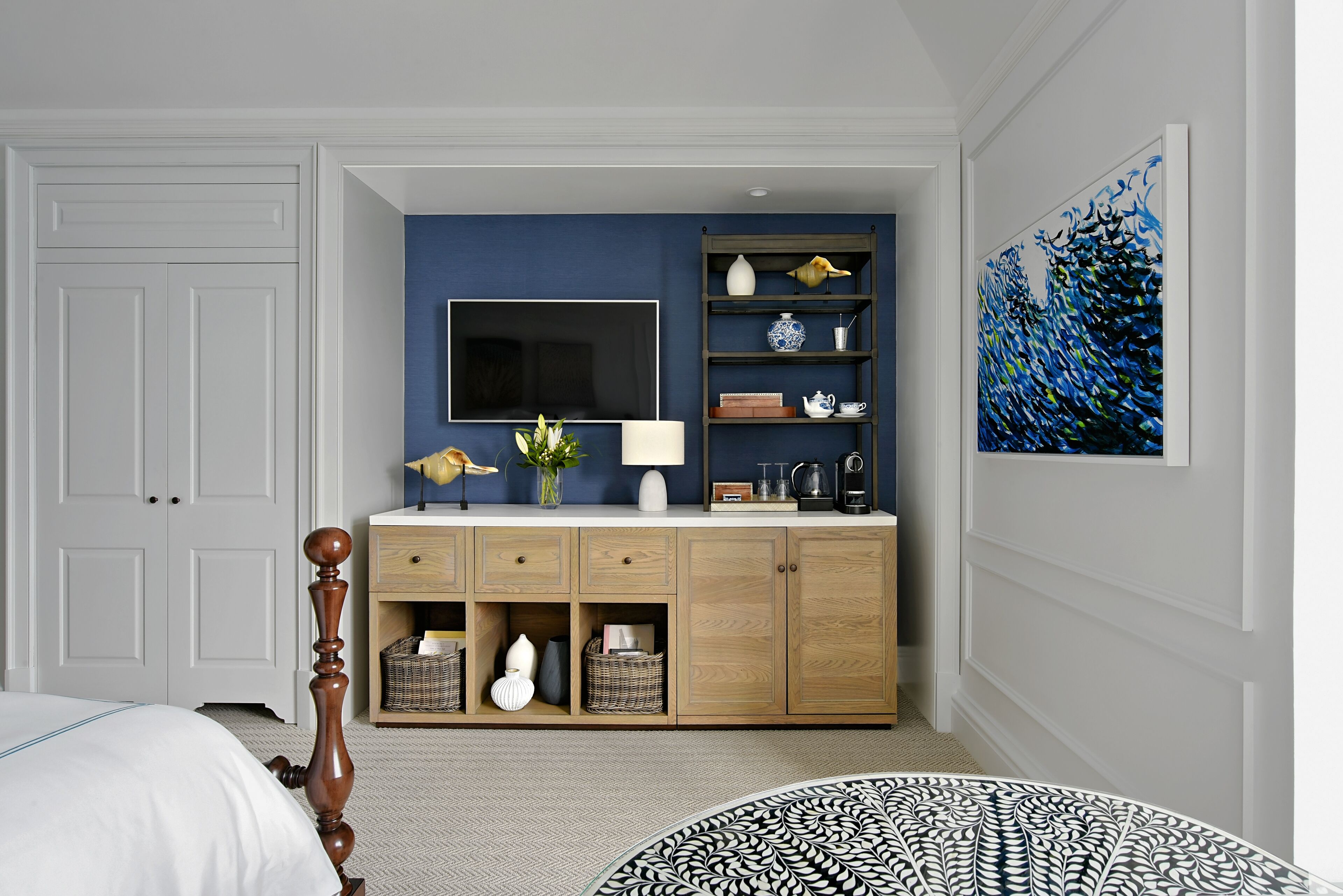 A bedroom with a bed, a dresser, a TV, and a painting.