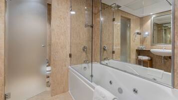 Un baño moderno con ducha de vidrio, una bañera amplia y un lavamanos con espejo.