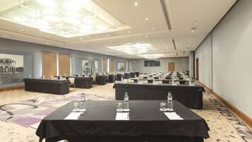 A conference room with multiple tables and chairs, equipped with water bottles and nameplates.