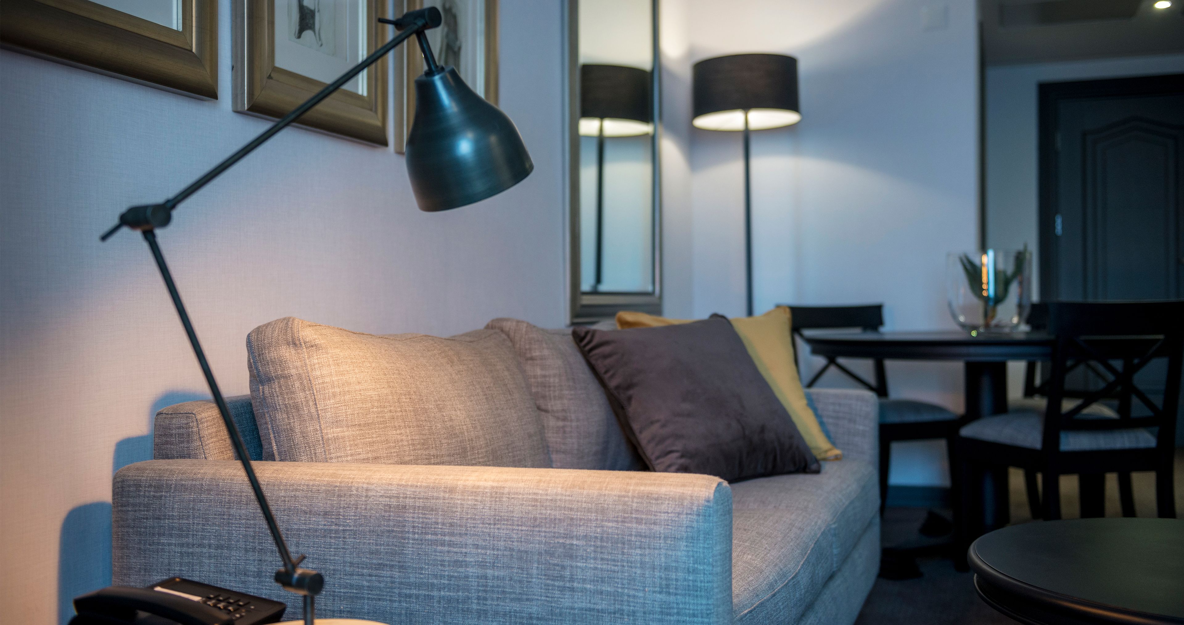 A living room with a sofa, a lamp, a table, and a chair.