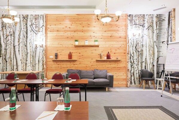 Una sala de conferencias con pared de madera, sillas rojas, un sofá gris y una pizarra.