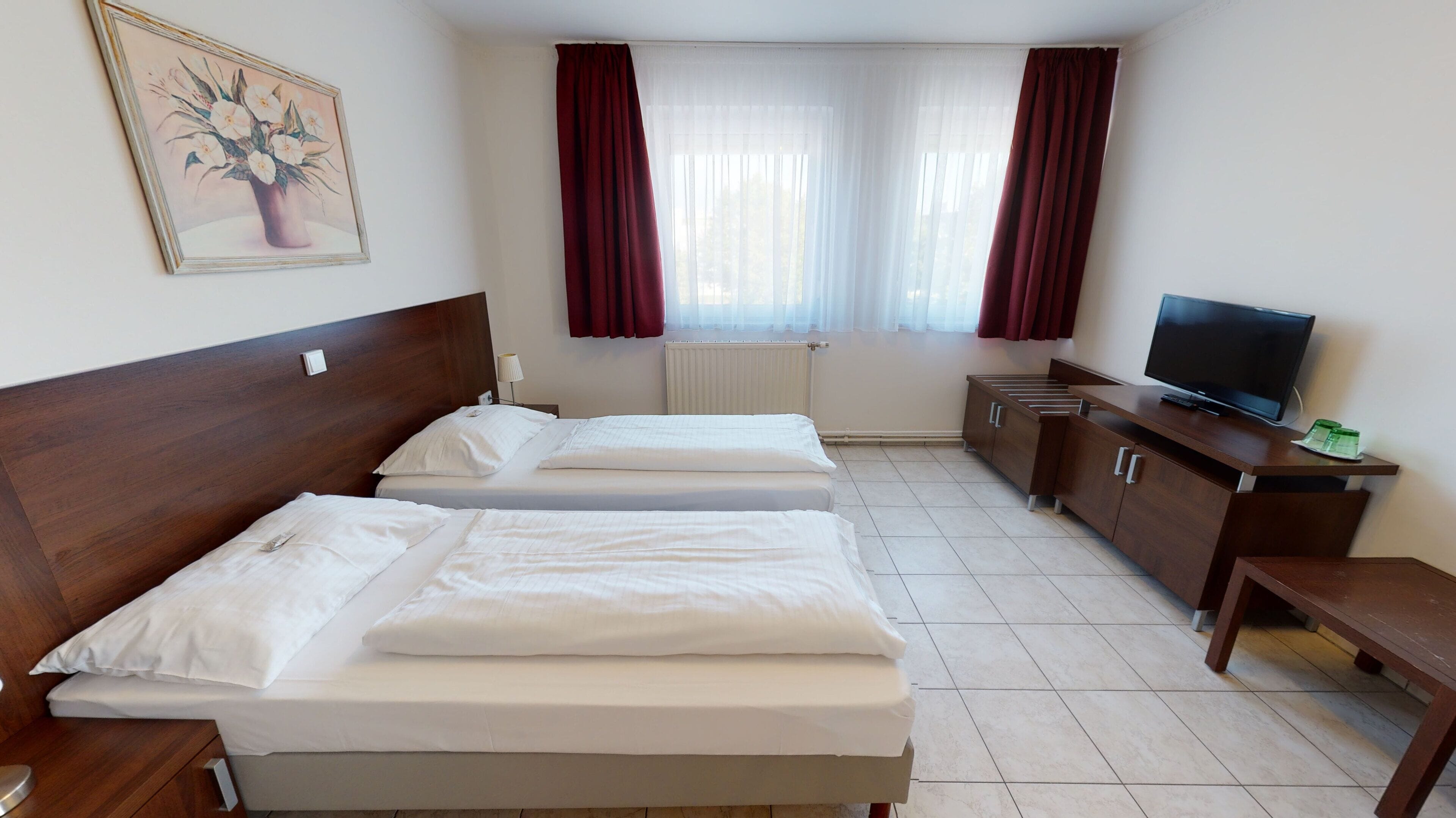Une chambre d’hôtel avec deux lits, une télévision, un bureau et un radiateur.