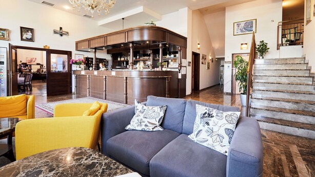 A spacious lobby with a bar area, a staircase, and seating arrangements. - Hotel San Marco (Lannach)