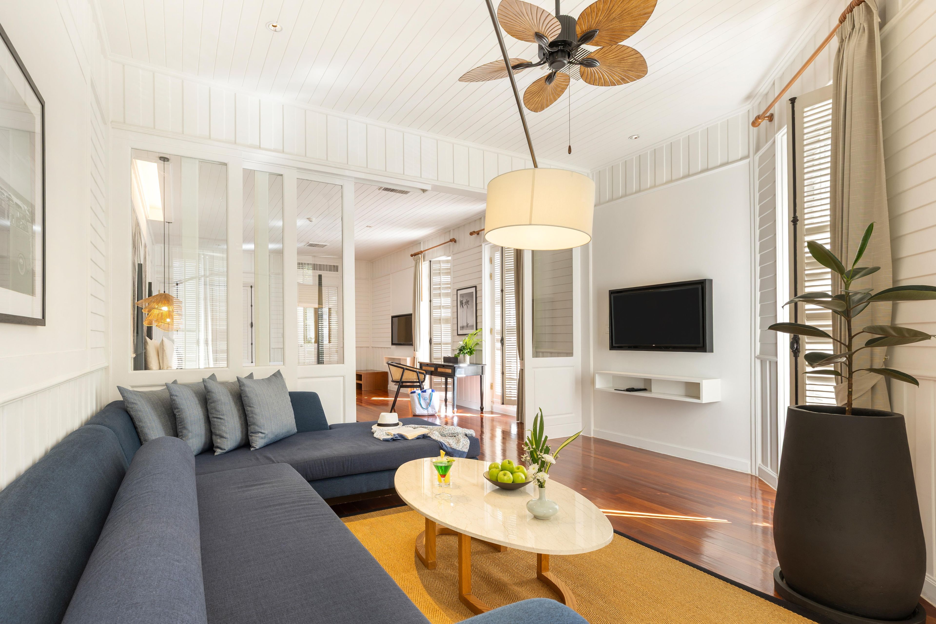 A modern living room with a sectional sofa, a round coffee table, a large floor lamp, and a TV mounted on the wall.