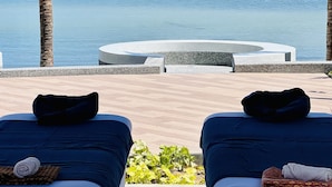 Dos tumbonas con toallas, una piscina y vistas al mar.