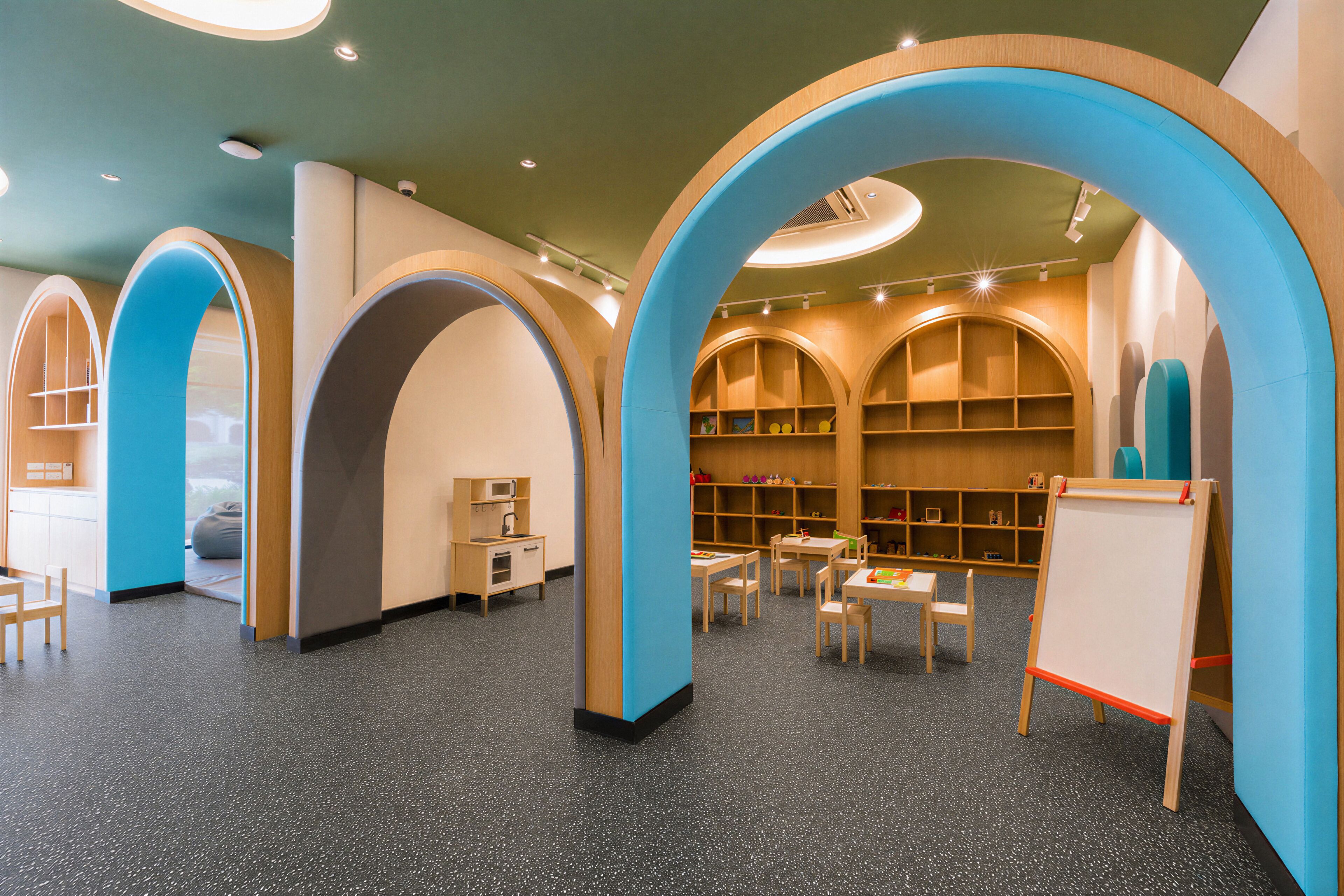 A children's library with wooden bookshelves, tables, chairs, and a whiteboard.