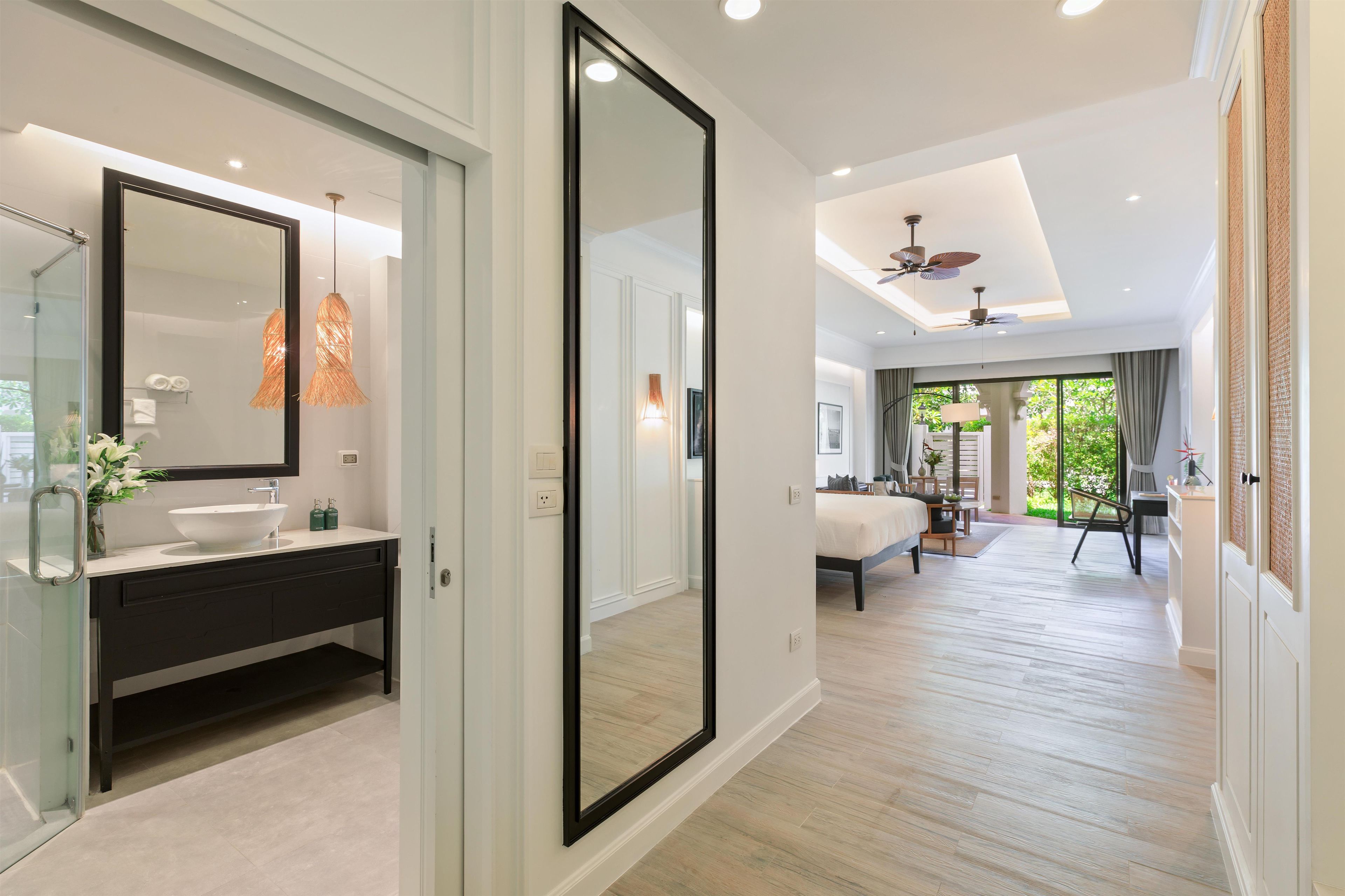 A modern bathroom with a large mirror, a glass shower enclosure, and a white sink.