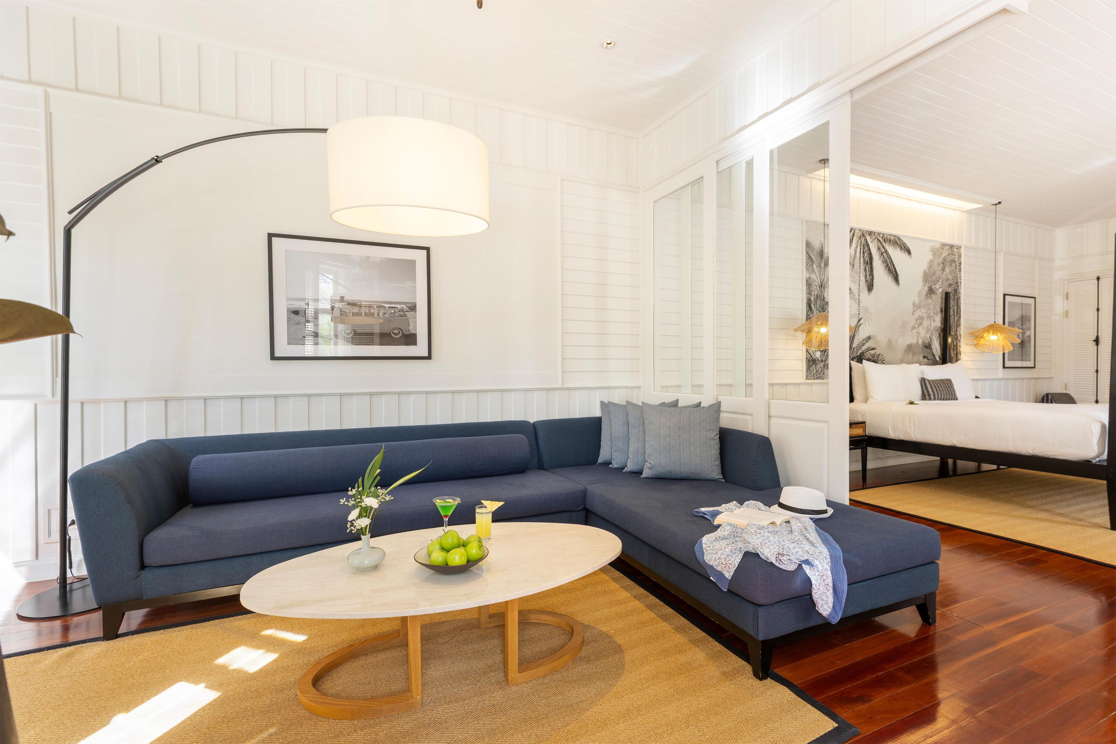 Una sala de estar moderna con un sofá sectional azul, una mesa de centro redonda y un cuadro en la pared.