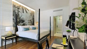 A four-poster bed, a desk with a notebook, a glass of drink, and a wall with a tropical mural.