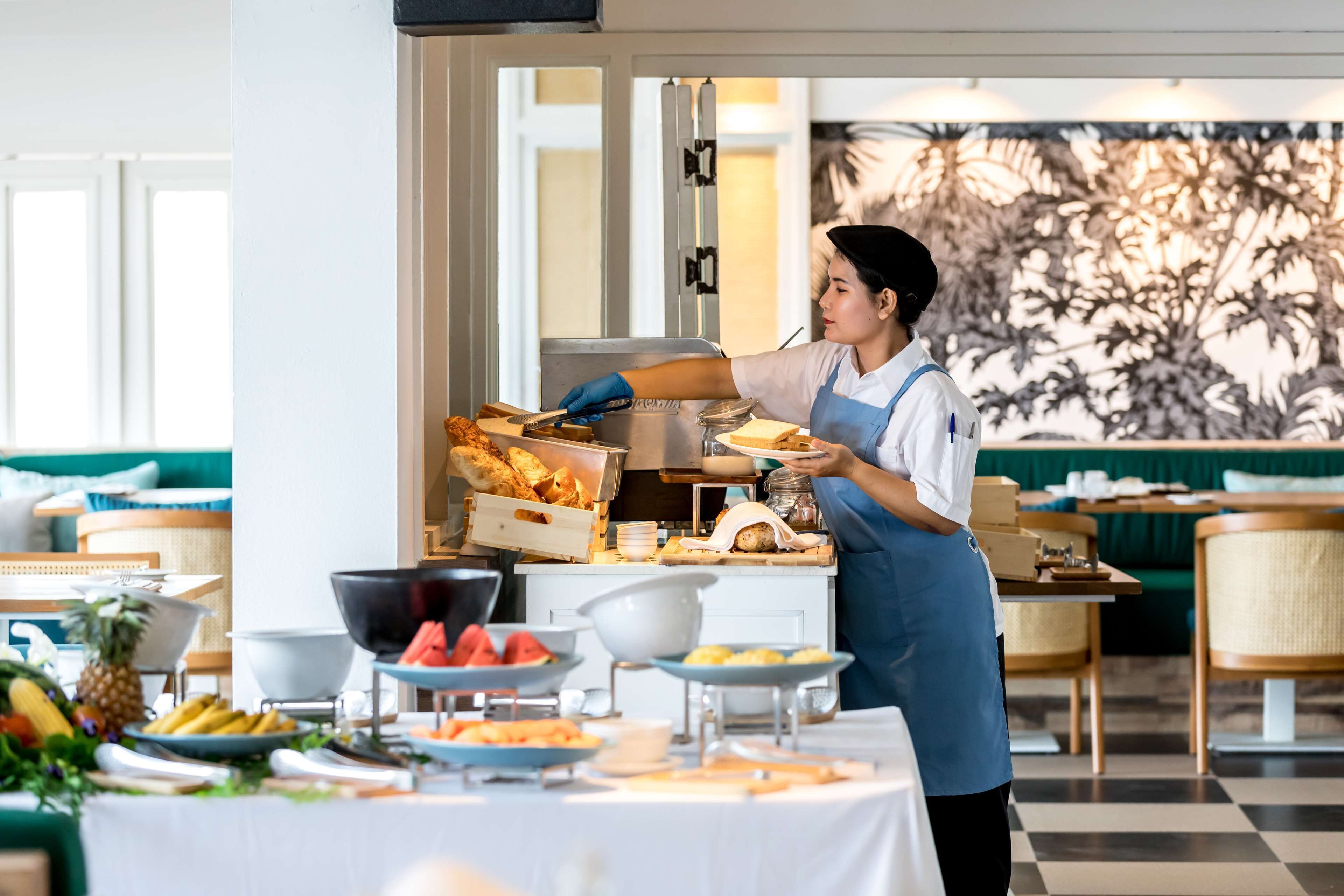 A buffet setup with various food items and a person serving.
