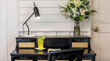 A desk with a lamp, a vase with flowers, and a glass of drink.