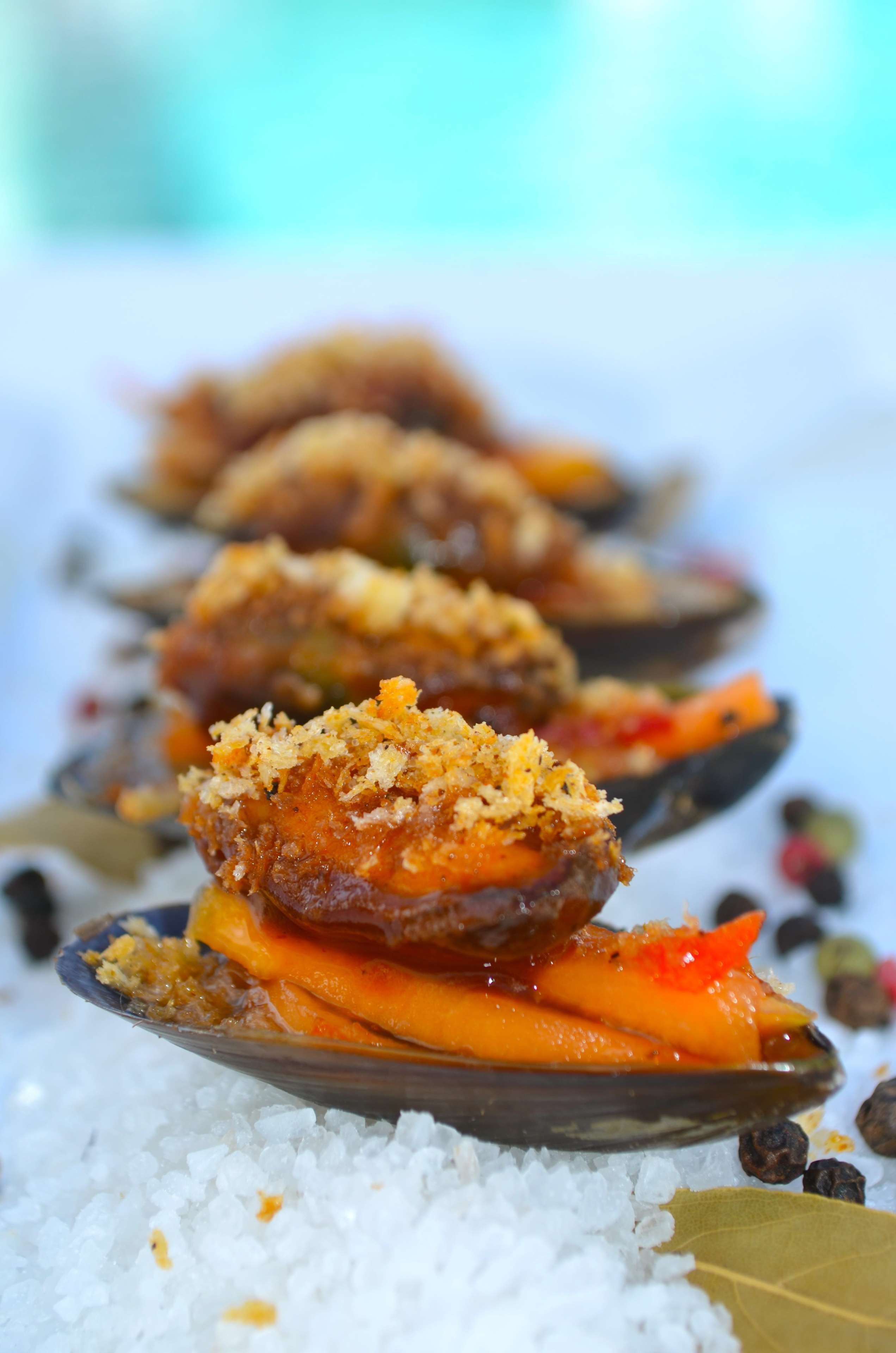 A dish of mussels with breadcrumbs and vegetables on a bed of rice.