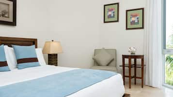 Habitación de hotel con una cama grande, una mesita de noche con lámpara, una silla y dos cuadros en la pared.