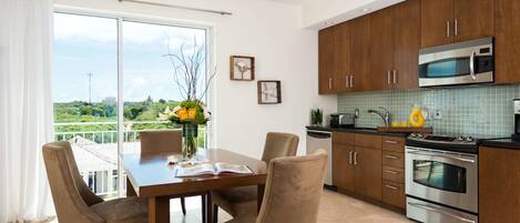 A modern kitchen with wooden cabinets, stainless steel appliances, and a dining area with a table and chairs.