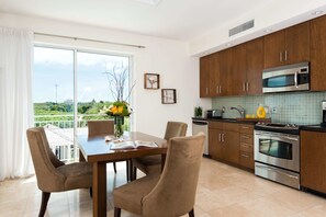 A modern kitchen with wooden cabinets, stainless steel appliances, and a dining area with a table and chairs.
