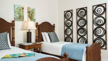 A hotel room with two wooden beds, a nightstand with a lamp, and artwork on the walls.