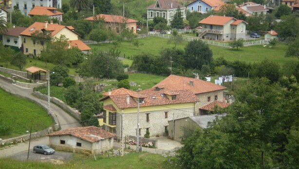 Un pueblo rural con casas de piedra y un camino sinuoso.
