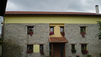 A stone building with a yellow facade and a tiled roof.