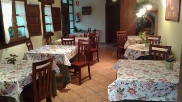 Un comedor con varias mesas y sillas, cada una cubierta con manteles florales.