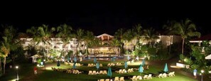 Un resort con piscina, sillones de descanso y palmeras.