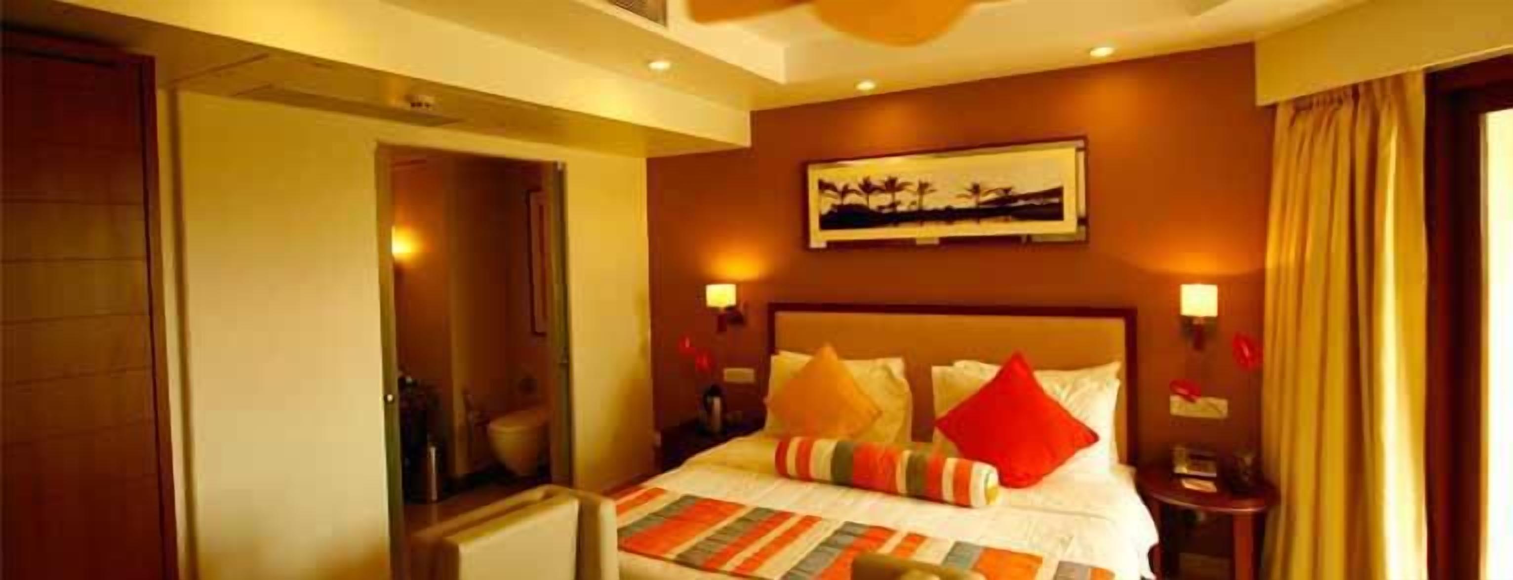 A hotel room with a bed, a painting on the wall, and a view of the bathroom.