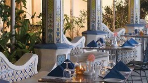 Een restaurant met gedekte tafels, met blauw-witte stoelen en een decoratief middelpunt.