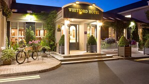 Ingången till Whitford Hotel, med en cykel parkerad utanför, trappsteg som leder upp till ingången och krukväxter runt om i området.