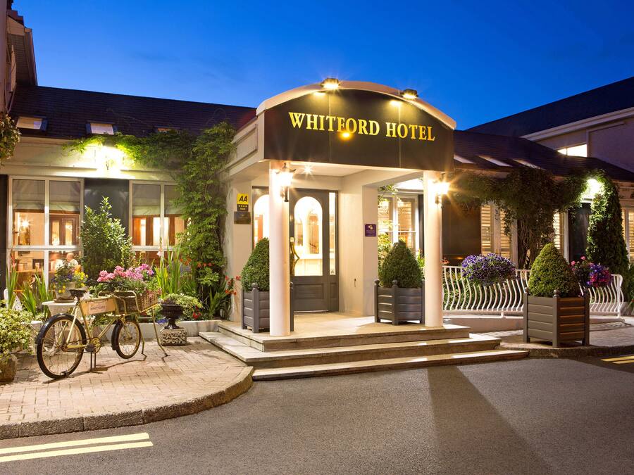 Der Eingang des Whitford Hotels mit einem draußen abgestellten Fahrrad und Stufen, die zum Eingang führen, sowie Pflanzkübeln in der Umgebung.