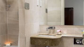 Un baño moderno con azulejos color beige, ducha, lavamanos con espejo y retrete.