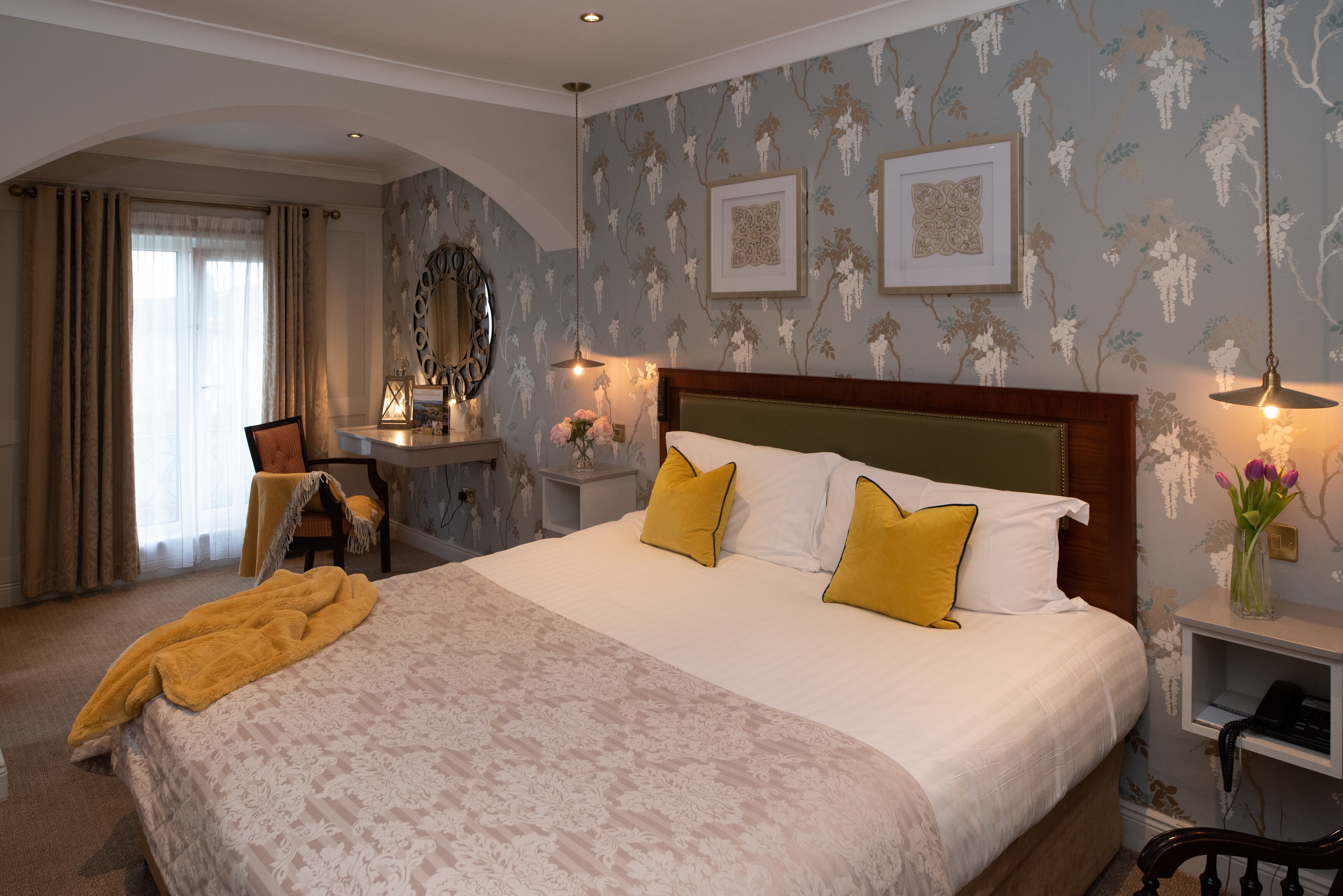 A neatly arranged bedroom with a large bed, a desk, and a chair.