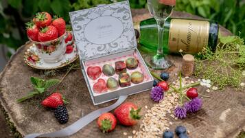 A table with a tea set, a bottle of wine, a gift box, and various fruits and berries.