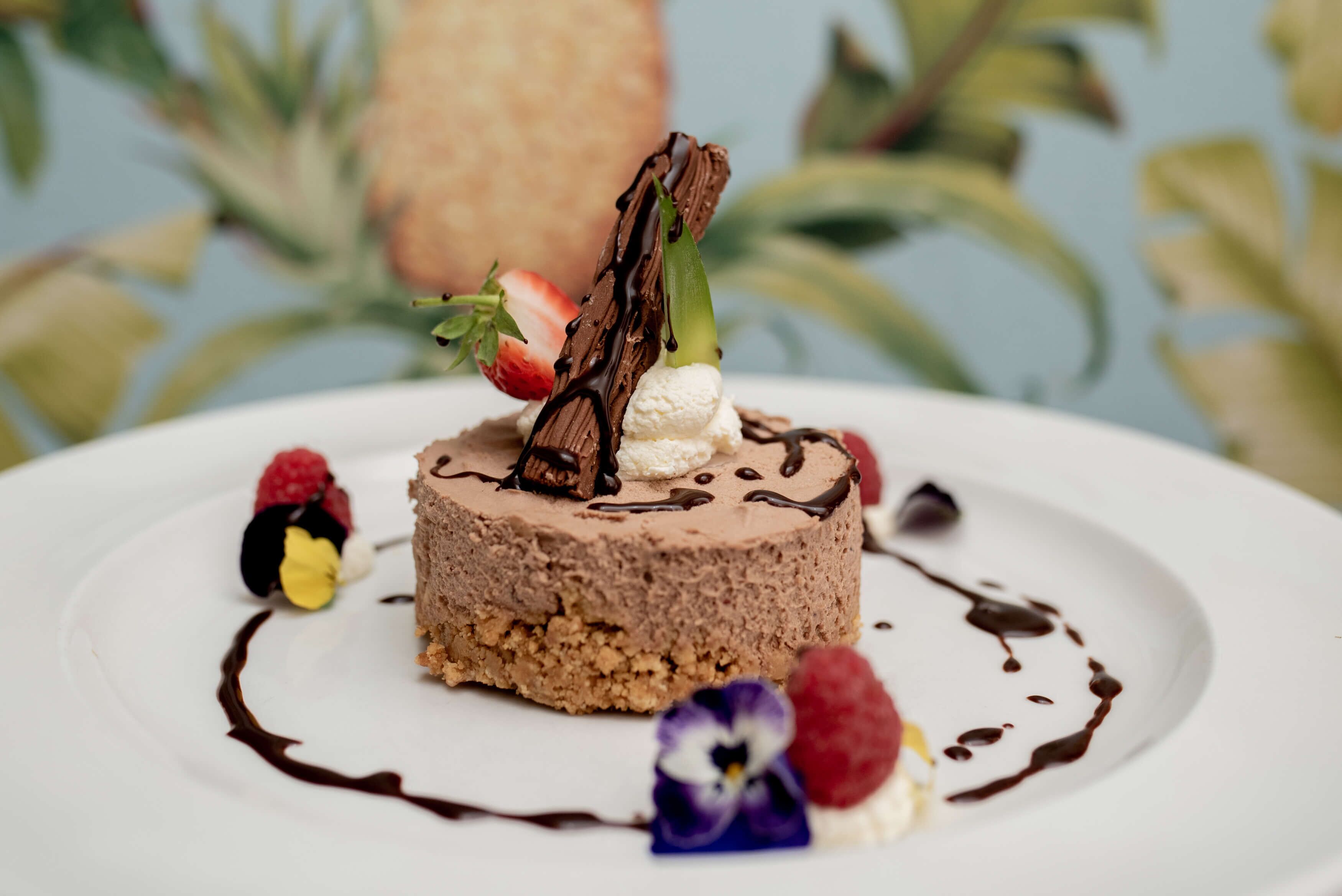 A dessert on a white plate with chocolate and strawberries.