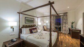 A four-poster bed with a swan-shaped centerpiece, a bedside telephone, and a nightstand. - Club Mahindra Munnar (Devikolam)