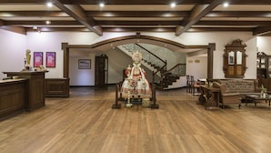 A lobby with a wooden reception desk, a grand staircase, and a traditional dress display. - Club Mahindra Munnar (Devikolam)