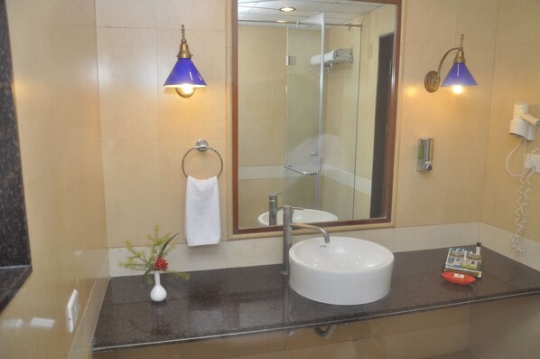 A bathroom with a round sink, a mirror, a towel ring, and two wall-mounted lamps. - Club Mahindra Kumbhalgarh (Rajsamand)