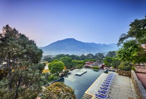 A rooftop infinity pool with a view of a mountain, surrounded by lush greenery and a clear sky. - Club Mahindra Kumbhalgarh (Rajsamand)