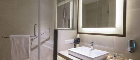 A modern bathroom with a glass shower enclosure, a large mirror, a sink, and a towel rack.