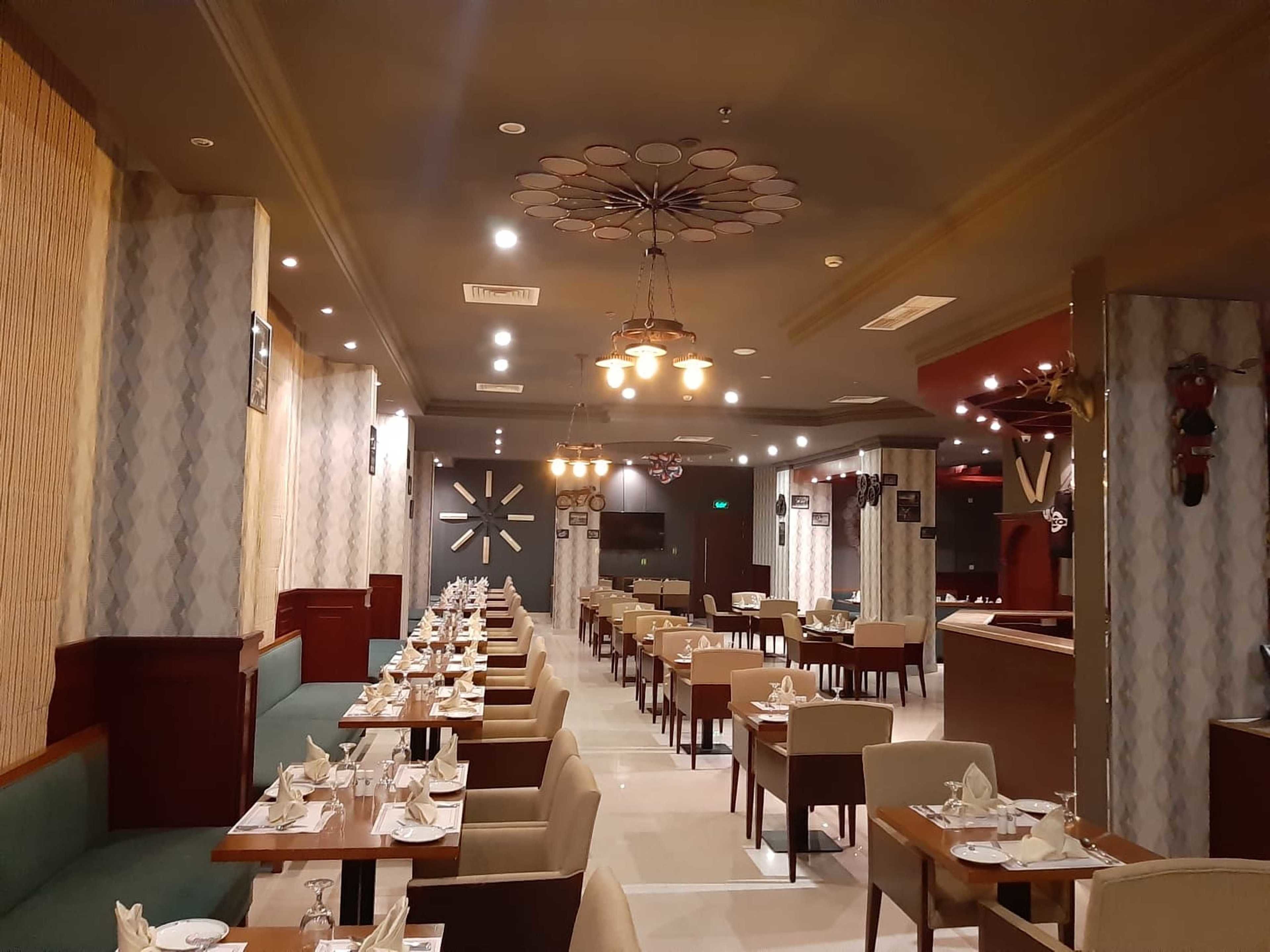 Un restaurante con mesas largas, cabinas y una lámpara de araña moderna.