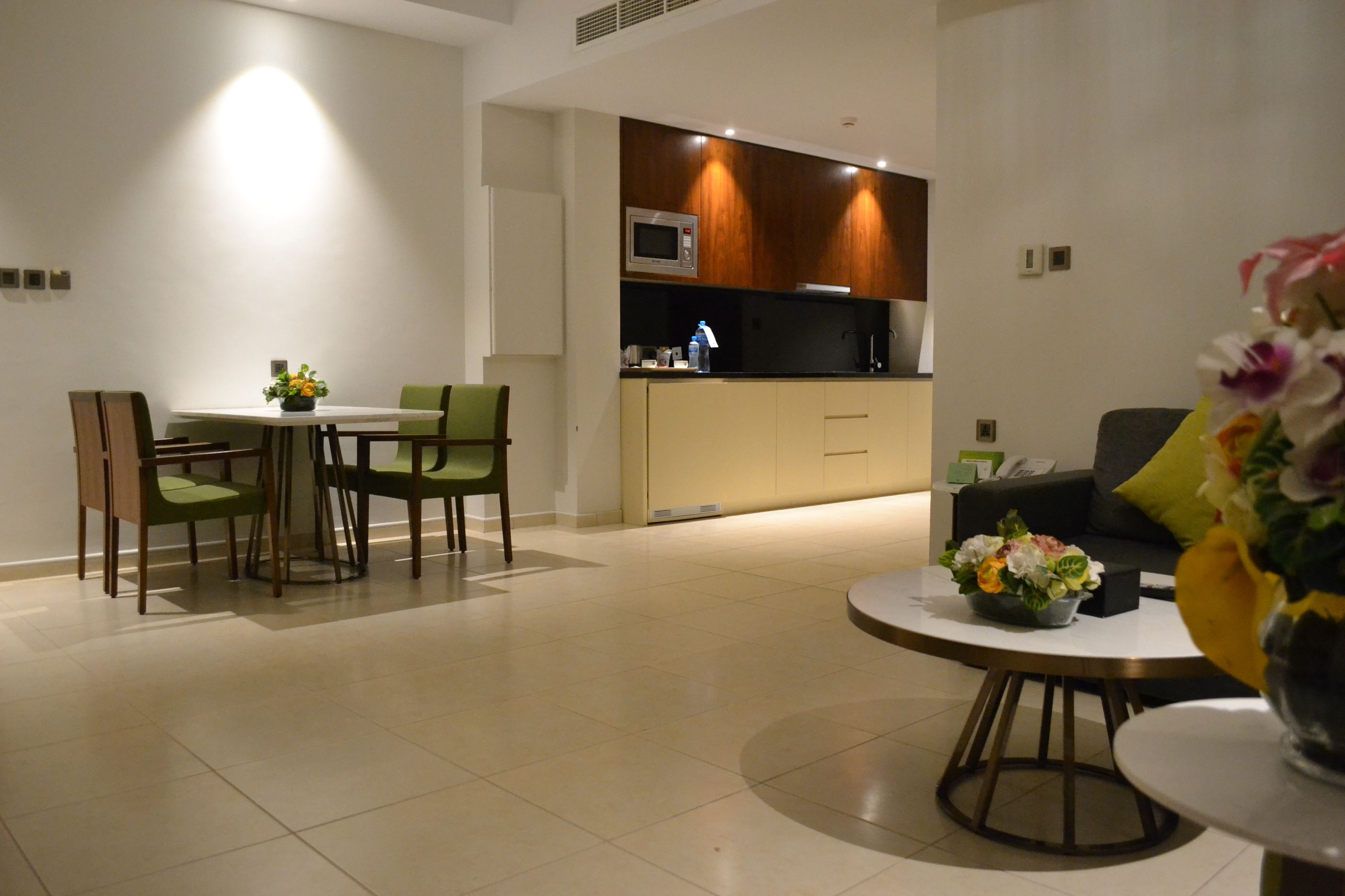 A modern living room with a dining area, a kitchen with a microwave, and a round coffee table.