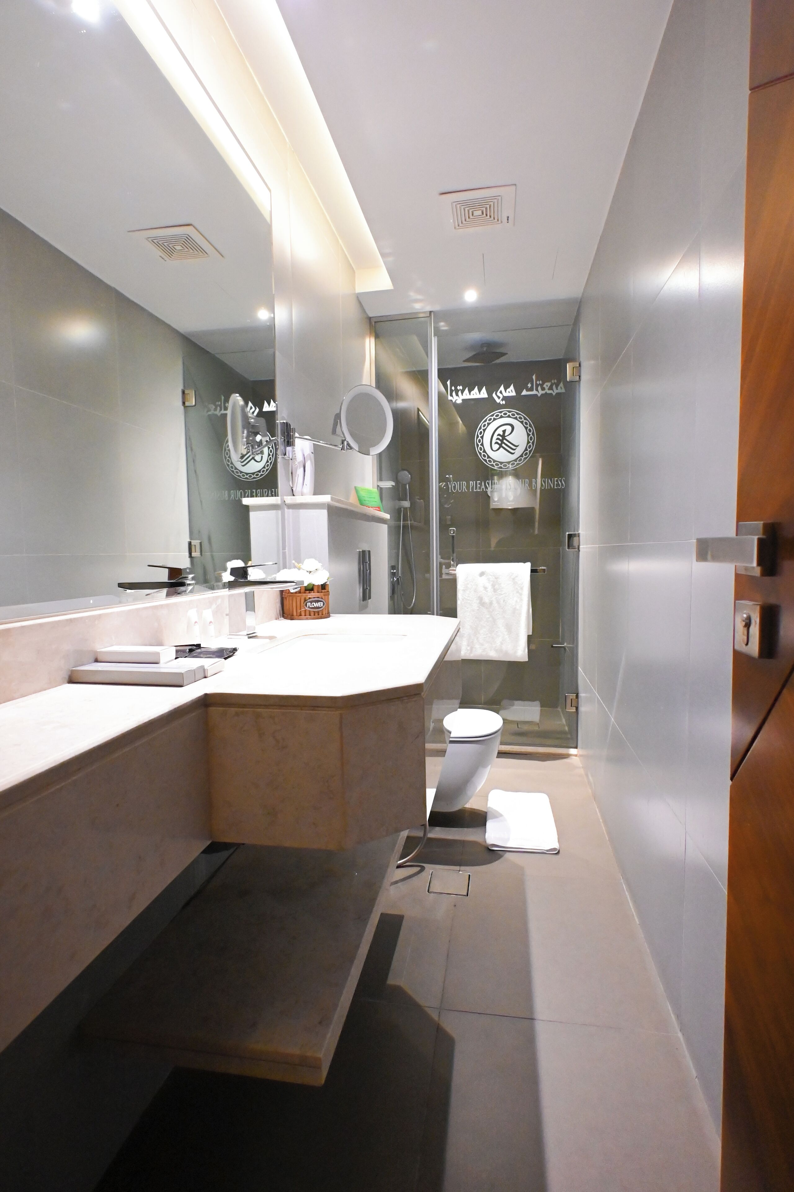 A modern bathroom with a large mirror, a sink, a toilet, and a shower area.